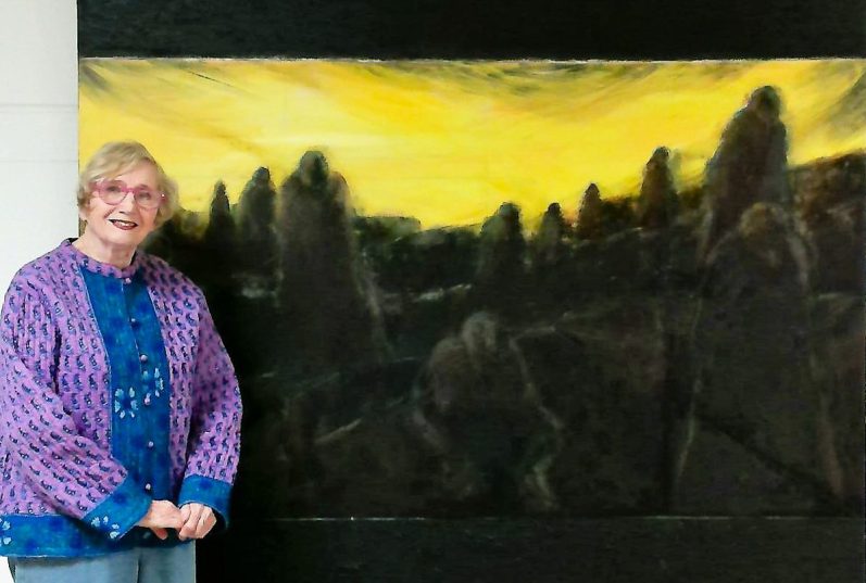 ,Judith Jaffe standing next to her painting titled "Monuments"
